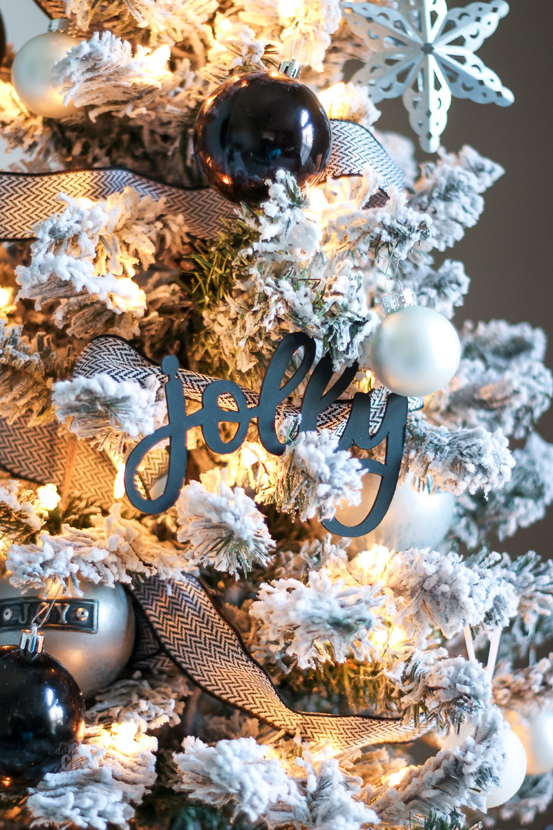 Close up word jolly ornament on flocked black and white decorated Christmas tree