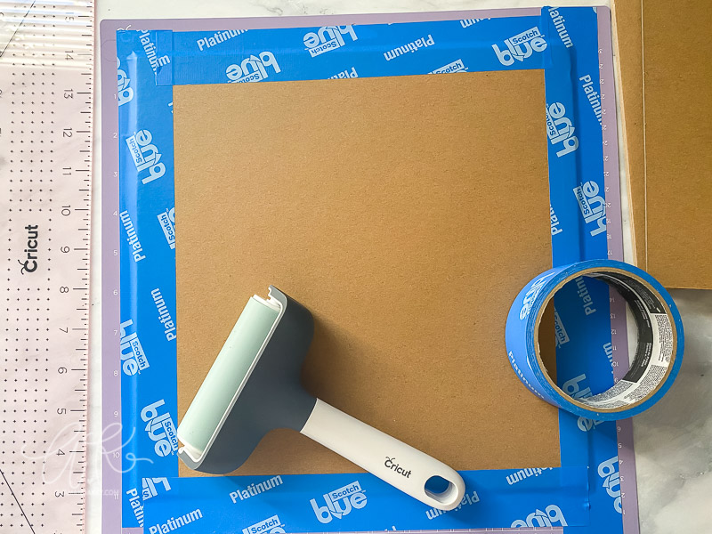overhead view of chipboard material taped down to strong grip mat with painters tape